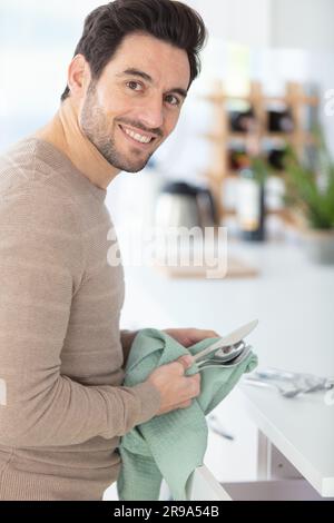 young man washing and drying the dishes at home Stock Photo