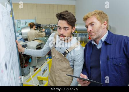two young creative engineers working on drawing board Stock Photo