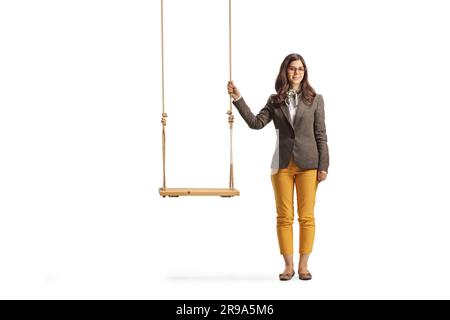 Full length portrait of a young female standing next to an empty wooden swing isolated on white background Stock Photo