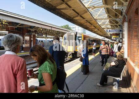 Friday commuters and rail travellers waiting on a platform at Basingstoke railway station for a South Western Railway train arriving. England Stock Photo