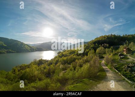 Panoramic aerial shot of Siriu Lake in Romania during early may on a sunny day. Cinematic drone shot with light clouds in the sky Stock Photo