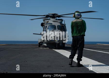 Aviation Structural Mechanic 3rd Class Ian Fincher, from Tyler, Texas, assigned to the 'Spartans' of Helicopter Maritime Strike Squadron (HSM) 70, guides an NH90 NATO Frigate Helicopter to land on the flight deck of the world's largest aircraft carrier USS Gerald R. Ford (CVN 78), June 19, 2023. This NH90 Frigate helicopter landing was the first time an Italian helicopter landed on a Ford-class aicraft carrier. Gerald R. Ford is the U.S Navy's newest and most advanced aircraft carrier, representing a generational leap in the U.S. Navy's capacity to project power on a global scale. The Gerald R Stock Photo