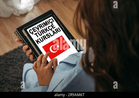 Online learning concept. A woman holds a tablet in her hands on the screen of which it is written - Online Turkish courses. Turkish inscription. Stock Photo
