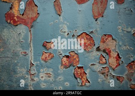 Weathered blue wall with pealing paint on a rusty surface in red color Stock Photo