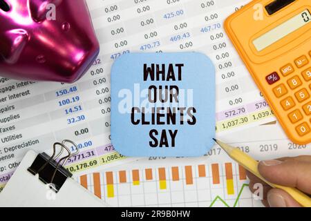 Business and economy concept. There are two notebooks and a pen on the table. On the top notepad, the inscription - What Our Clients Say Stock Photo
