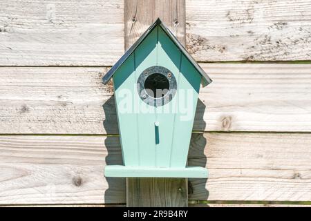 Blue birdhouse on a wooden fence in a garden Stock Photo