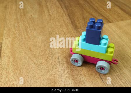 Plastic building blocks form vehicle on wooden background Stock Photo