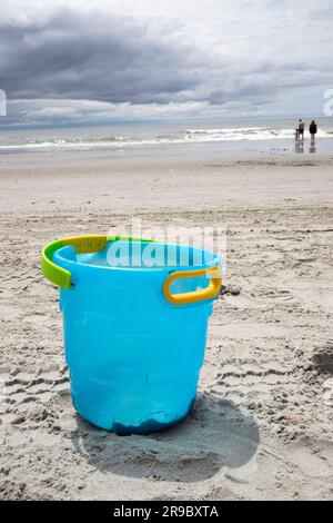 abandoned blue bucket on the sand at the beach, not being played with, copy space Stock Photo