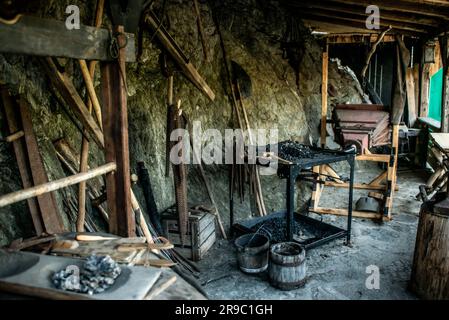 View of traditional blacksmith's shop for forging medieval iron, with furnace and an ancient bellows blower. Stock Photo