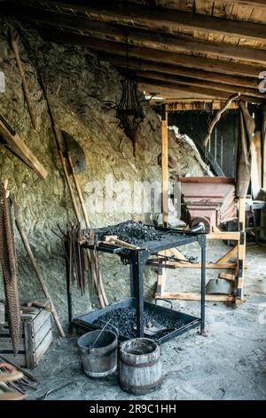 View of traditional blacksmith's shop for forging medieval iron, with furnace and an ancient bellows blower. Stock Photo