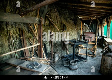 View of traditional blacksmith's shop for forging medieval iron, with furnace and an ancient bellows blower. Stock Photo