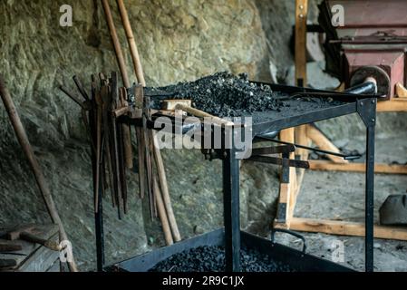 View of traditional blacksmith's shop for forging medieval iron, with furnace and an ancient bellows blower. Stock Photo