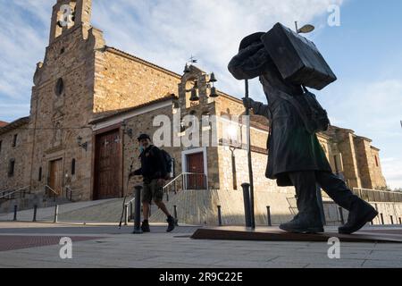 A pilgrim on the Camino Frances eyes the statue of a pilgrim at the Albergue de peregrinos Siervas de María as he arrives in Astorga, Spain. This anci Stock Photo