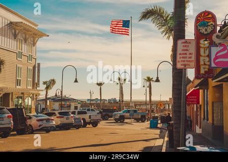 Pismo Beach, California, USA - March 2, 2023.   Pismo Beach Pier plaza. Shops, restaurants, traffic, walking people, downtown of city, city life Stock Photo