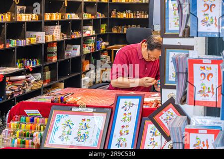 Sign writer and calligrapher working in shop at Stanley Market, Hong Kong, SAR, China Stock Photo
