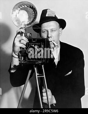 United States:   1938 A press photographer aims his flash camera. Stock Photo