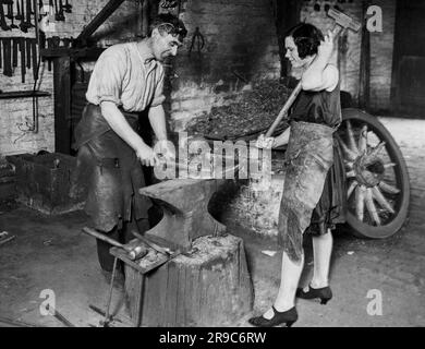 Wolverhampton, England:  1930 A wife at work as a striker with her husband in their blacksmith shop. Stock Photo