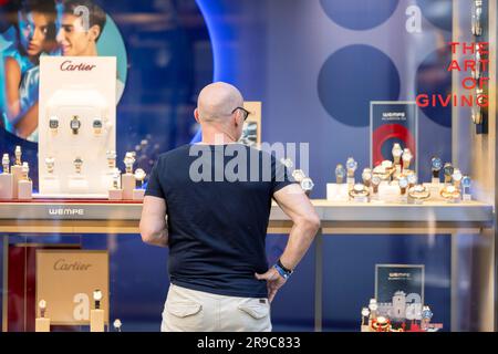 Cologne, Germany. 24th June, 2023. A passerby stands in front of a shop window of a watch and jewelry store in downtown Cologne. Credit: Thomas Banneyer/dpa/Alamy Live News Stock Photo