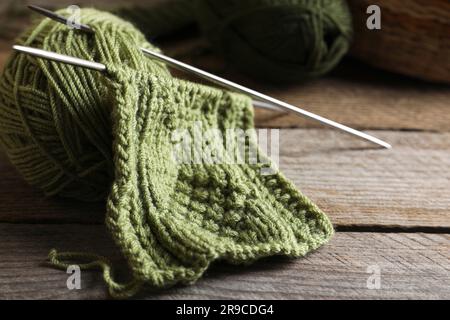Soft green woolen yarn, knitting and needles on wooden table, closeup Stock Photo
