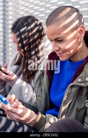 young woman using mobile phone with friends Stock Photo