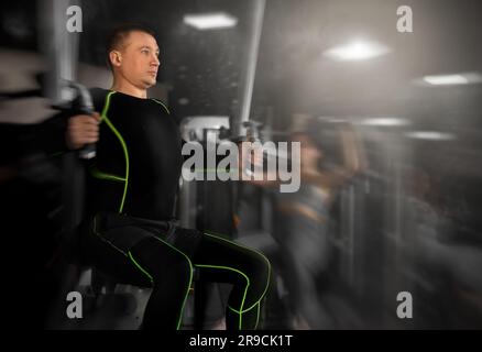 Portrait of concentrated adult man doing strength training in gym, performing chest muscles exercises on pec deck machine Stock Photo