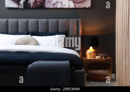Comfortable bed with cushions and ottoman in room. Stylish interior Stock Photo