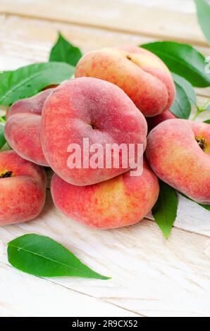 Fresh Flat Peaches, Chinese Saturn Donut Peaches with Leaves on Bright Background Stock Photo