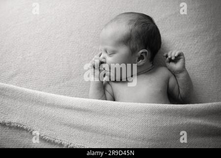 baby sucking thumb on a blanket in black and white Stock Photo