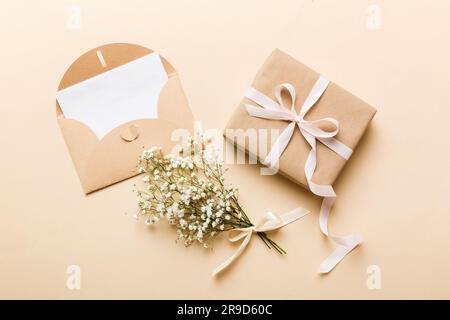 Wedding mockup with white paper list and flowers gypsophila on colored table top view flat lay. Blank greeting cards and envelopes. Beautiful floral p Stock Photo