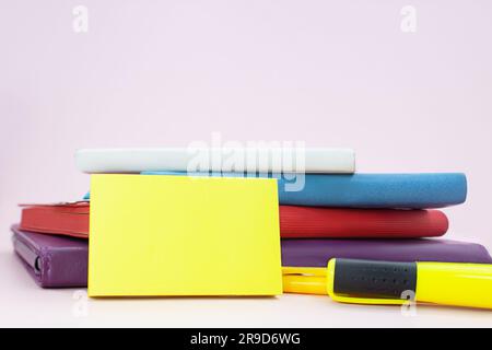 Stack of notepads with marker on pink table with sticky sticker. Back to school. Copy space Stock Photo