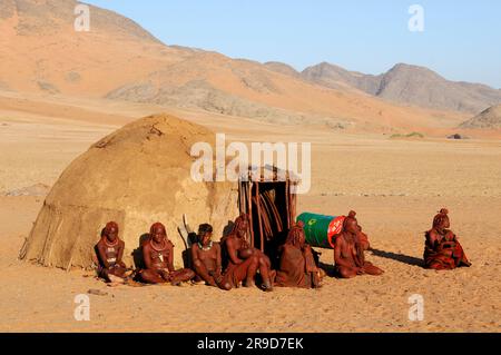 Himba women at hut, village near Serra Cafema Wilderness Safaris at Kunene River, Kunene Region, Namibia Stock Photo