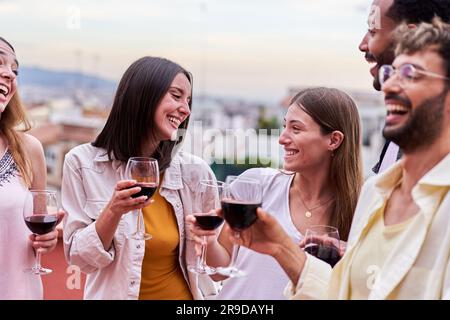 Friends having fun in a terrace, laughing, talking, and drinking red wine.  Stock Photo