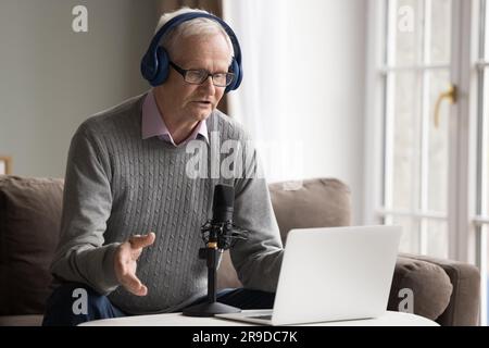 Older man in headphones makes speech into microphone Stock Photo