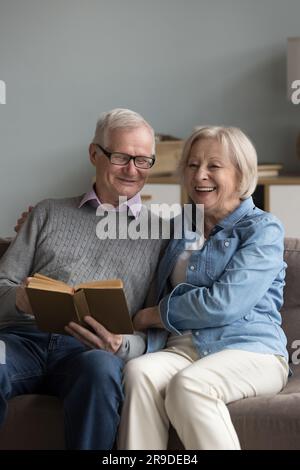 Retired husband and wife spend time reading book at home Stock Photo