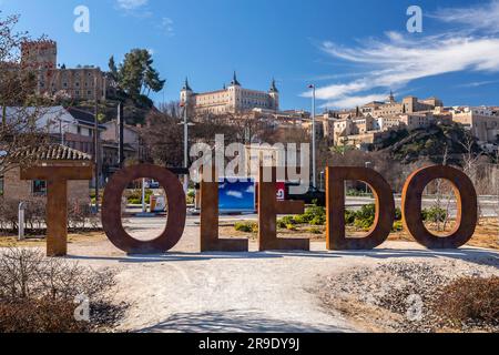 Toledo, Spain-FEB 17, 2022: Toledo name monument against the Alcazar of Toledo, a stone fortification located in the highest part of Toledo, Spain. Stock Photo