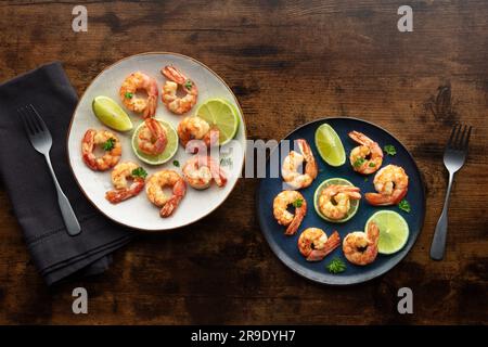 Shrimps, overhead flat lay shot. Fried shrimp with lime, two plates, shot from the top on a rustic wooden background Stock Photo