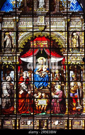 Ghent, Belgium - July 10, 2010 :  Stained glass window inside Saint Nicholas' Church. Image of Mary and baby Jesus surrounded by other holy people. Stock Photo