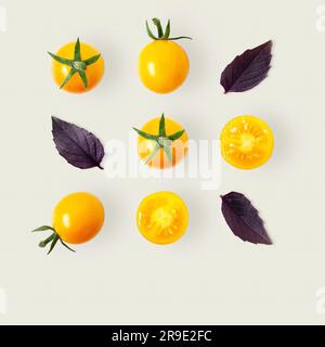 Square pattern of yellow cherry tomatoes and purple basil leaves on light grey background with copy space. Stock Photo