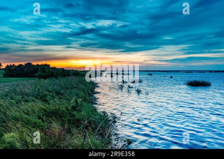 An aerial view of Lake Okeechobee surrounded by lush greenery at sunset in Florida, the United States Stock Photo