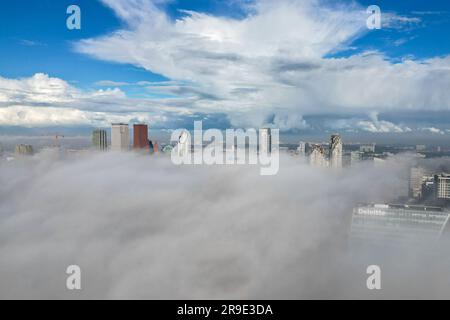 Aerial drone photo of the skyline in Den Haag. The tall skyscrapers can be seen above the clouds. Stock Photo