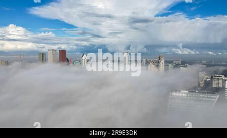 Aerial drone photo of the skyline in Den Haag. The tall skyscrapers can be seen above the clouds. Stock Photo