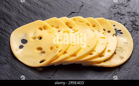 macro shot of sliced cheese with holes on a stone surface top view. sliced cheese on a white background Stock Photo