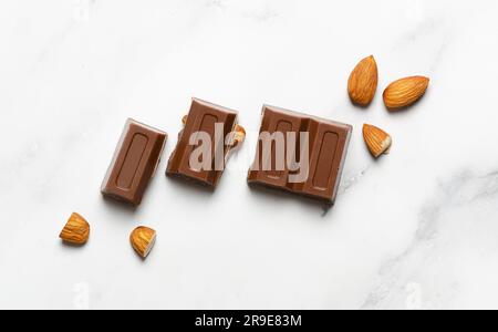 Milk chocolate with almonds on marble background. Stock Photo