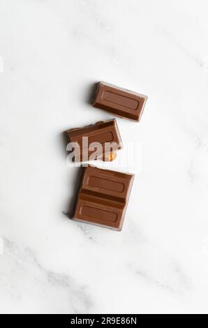 Milk chocolate with almonds on marble background. Vertical format. Stock Photo