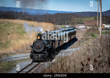 A Front and Slightly Above View of an Approaching Restored Narrow Gauge Passenger Steam Train Blowing Smoke and Steam on a Sunny Winter Day Stock Photo