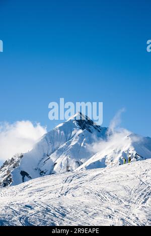 View of the a mountain, near the ski resort in Gudauri, Georgia with two skiers going towards the summit. Stock Photo