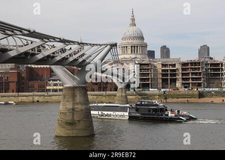 Uber boat passing under Millennium Bridge with St Pauls Cathedral London April 2022 Stock Photo