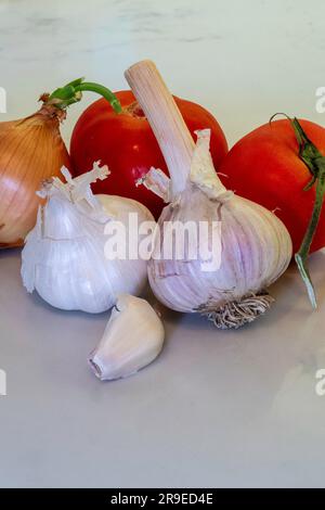 Still life of garlic, onion, and vine, ripened tomatoes on the kitchen counter, 2023, USA Stock Photo