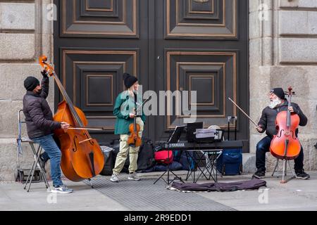 Madrid, Spain - FEB 19, 2022: Street musicians performing with double celloes and a violin in Calle de Alcala, Madrid. Stock Photo