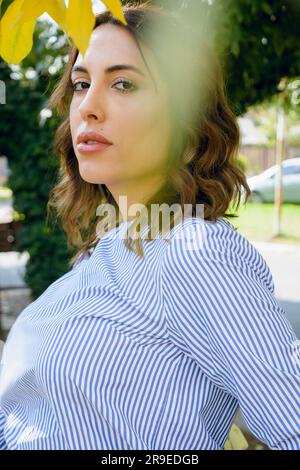 Vertical waist up portrait of young fashionable Latin business woman of Argentinian ethnicity, with healthy skin, long brown hair, dressed in casual c Stock Photo